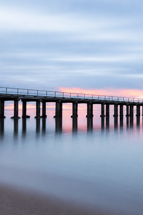 A long pier extending across still water toward the horizon