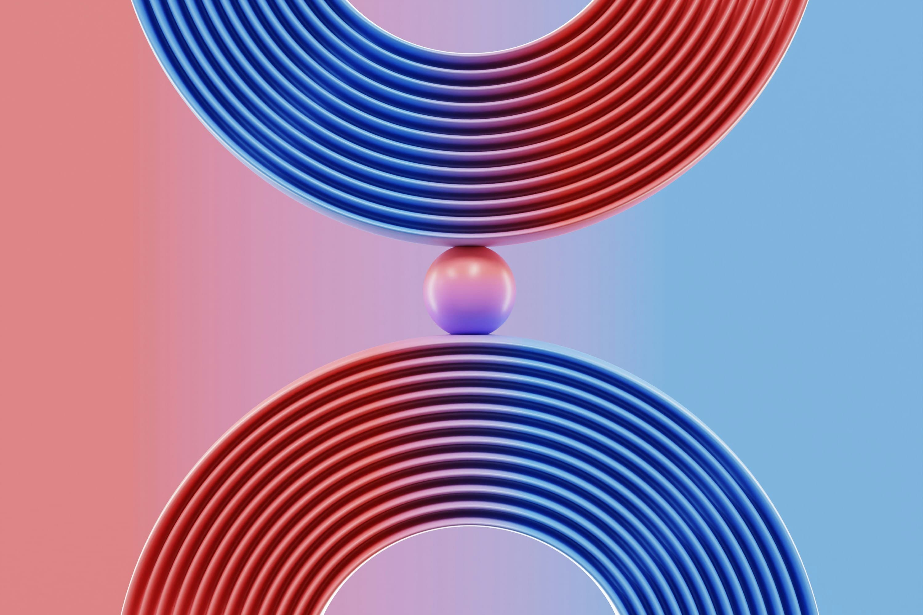 A small sphere held between two curved, ribbed forms in red and blue.